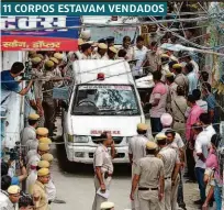 ??  ?? Van da polícia de Nova Déli retira um dos corpos de chacina; vítimas estavam penduradas em uma viga