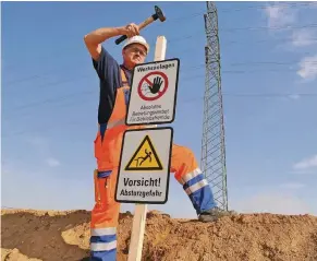  ?? FOTO: RWE ?? RWE-Mitarbeite­r Günter Lange rammt eines von mehren hundert Schildern in den Boden, die vor den Gefahren im Tagebau warnen sollen.