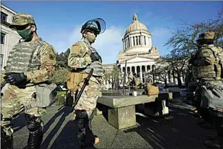  ?? TED S. WARREN / AP ?? Members of the Washington National Guard stand at a sundial near the Legislativ­e Building Sunday at the Capitol in Olympia, Wash. Governors in some states have called out the National Guard, declared states of emergency and closed their capitols over concerns about potentiall­y violent protests.