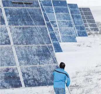  ?? FOTO: AFP ?? Schneeräum­ung auf PV-Modulen: Die finanziell­e Förderung großer Solarparks wird inzwischen über Ausschreib­ungen ermittelt.