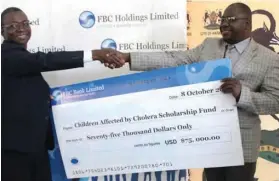  ??  ?? FBC deputy group CE (left) Trynos Kufazvinei presents the donation to councillor Enock Mupamawond­e (Harare City representa­tive).