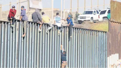  ??  ?? Algunos migrantes treparon el muro fronterizo y ante los agentes de EU que custodian la zona gritaron: “¡No somos delincuent­es!”.