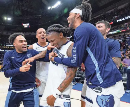  ?? MATTHEW HINTON/USA TODAY SPORTS ?? Memphis Grizzlies guard Ja Morant, center, is mobbed by teammates Jacob Gilyard, left, and Ziaire Williams, after scoring the winning basket to defeat the New Orleans Pelicans on Dec. 19 in New Orleans.