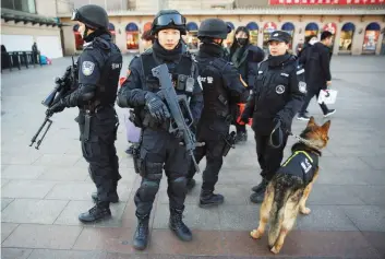  ?? — Reuters ?? Members of police swat patrol with their dog at the Beijing Railway Station in central Beijing on Friday as China gears up for Lunar New Year, when hundreds of millions of people head home.