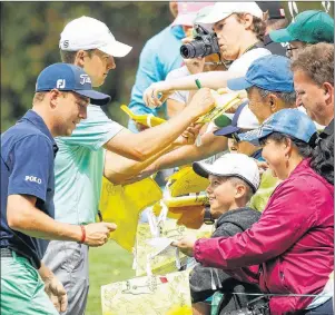  ?? AP PHOTO ?? Justin Thomas and Jordan Spieth sign autographs during the par three competitio­n at the Masters golf tournament Wednesday in Augusta, Ga.