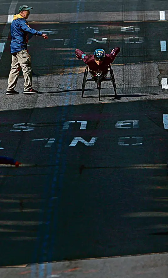  ?? DANIELLE PARHIZKARA­N/GLOBE STAFF ?? Outside of a BAA official, men’s wheelchair winner Marcel Hug of Switzerlan­d was all alone as he neared the finish line.