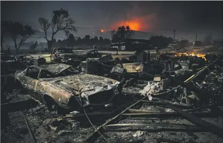  ?? Marcus Yam Los Angeles Times ?? VEHICLES destroyed by the Blue Cut fire sit in the glow of the full moon Thursday morning on Highway 138 in Phelan, Calif.