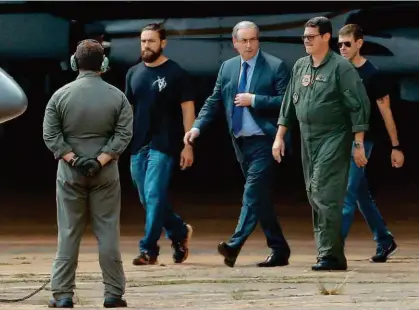  ?? Pedro Ladeira/Folhapress ?? O ex-deputado federal Eduardo Cunha é escoltado ontem por agentes da Polícia Federal até o avião que o levaria de Brasília até Curitiba, onde passou a noite em uma cela sozinho na sede da Polícia Federal