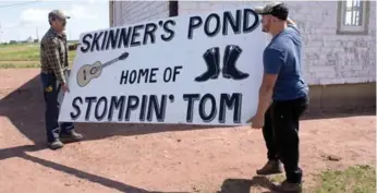  ?? ANDREW VAUGHAN/THE CANADIAN PRESS ?? Workers move a sign at the site of the proposed Stompin’ Tom Connors cultural centre in Skinners Pond, P.E.I.