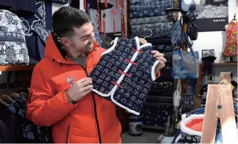  ??  ?? Taylor Rochestie, a U.S. basketball player with a Tianjin-based club, buys a traditiona­l Chinese jacket for his daughter in a store in the north Chinese port city on December 13, 2018