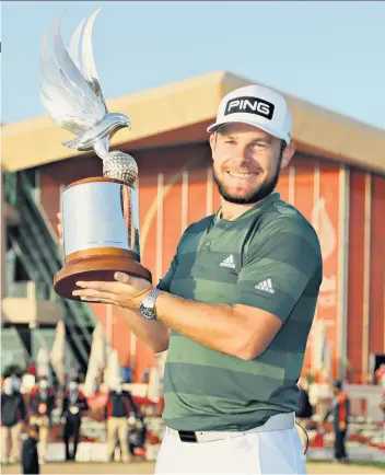  ??  ?? Flying high: Tyrrell Hatton shows off the Falcon Trophy after victory in Abu Dhabi (above) and kisses fiancee Emily Braisher (below)