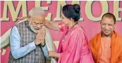  ?? —PTI ?? PM Narendra Modi being greeted with a shawl by the local BJP MP Hema Malini as CM Yogi Adityanath looks on in Vrindavan near Mathura, Monday.