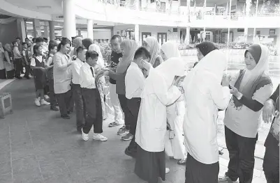  ??  ?? CALON Ujian Pencapaian Sekolah Rendah, Sekolah Kebangsaan Dato Traoh di Kota Samarahan bersalaman dengan ibu bapa dan guru.