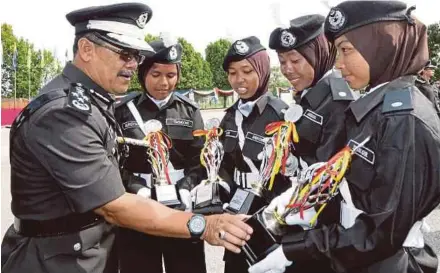  ?? PIC BY L. MANIMARAN ?? Prisons Department director-general Datuk Seri Zulkifli Omar looking at a cadet’s award at the Correction­al Graduates’ End-of-Training parade at the Prison Officers Training Centre in Taiping yesterday.