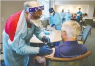  ?? JOE RAEDLE/GETTY IMAGES ?? A health-care worker administer­s a Pfizer-BioNTech COVID-19 vaccine at a retirement community in
Pompano Beach, Fla., on Wednesday.