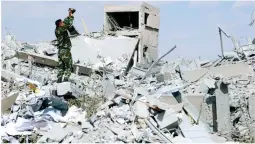  ??  ?? A Syrian soldier films the damage of the Syrian Scientific Research Center which was attacked by US, British and French military strikes to punish President Bashar Assad for suspected chemical attack against civilians, in Barzeh, near Damascus, Syria,...