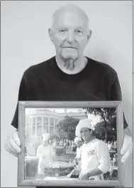  ?? Lynn Atkins/The Weekly Vista ?? Del Allen shows off a photograph of two of his former employees grilling fish on the White House lawn. He brought his charcoal grill from his seafood restaurant in California to feed President Ronald Reagan and all of congress at an annual cook out in...