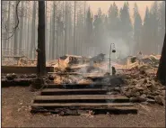  ?? (AP/Eugene Garcia) ?? Smoke comes out under the front steps of a house Sunday that burned along North Arm Road in Plumas County near Taylorsvil­le, Calif.