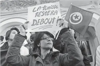  ?? SOFIENE HAMDAOUI, AFP/GETTY IMAGES ?? A woman holds a placard reading in French, “Tunisia will remain standing ” as she takes part in a protest March 18, 2015, after an attack on the National Bardo Museum in Tunis.