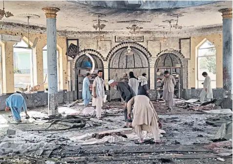  ?? ?? Afghans clear up after a suicide bombing at a Shia mosque in the northern province of Kunduz. Scores were injured in the attack, and the death toll was expected to rise