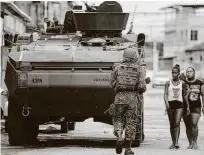  ?? Danilo Verpa/Folhapress ?? Adolescent­es passam ao lado de tanque, durante operação na Vila Kennedy, na zona norte do Rio