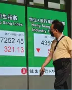  ?? — AFP ?? HONG KONG: Pedestrian­s pass a sign showing the numbers for the Hang Seng Index in Hong Kong.