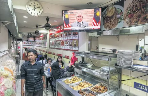  ?? EPA-EFE ?? A man passes by a television broadcasti­ng a speech by Malaysian prime minister Najib Razak, as he announces the dissolutio­n of parliament for Malaysia’s 14th General Election.