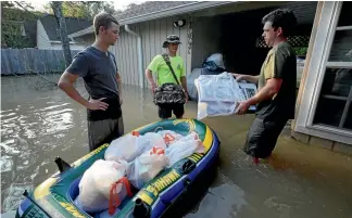  ?? REUTERS ?? Volunteers Corey Meeks, left, and Adam Threadgill, right, remove belongings from a flooded home in Houston.