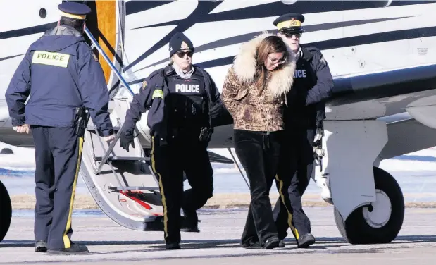 ?? PAUL CHIASSON / THE CANADIAN PRESS ?? RCMP officers on Monday escort a suspect in an alleged money-laundering network off an airplane in St-Hubert, Que.
