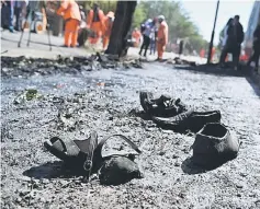  ??  ?? Footwear of victims are seen on the ground as Afghan residents inspect the site of a car bomb attack in western Kabul. — AFP photo