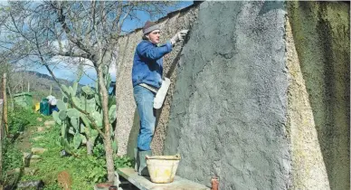  ?? AUDREY RODEMAN VIA AP ?? Cain Burdeau covers a wall of a small concrete house where he lives with his family outside Castelbuon­o, Sicily, Italy, in a coat of concrete plaster.