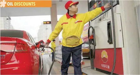  ?? — Reuters ?? A gas station attendant pumps fuel into a customer’s car at PetroChina’s petrol station in Beijing.