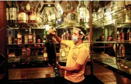  ?? — PTI ?? An employee wearing face shield and hand gloves cleans the counter of a bar at Connaught Place ahead of its reopening during Unlock 4 in New Delhi on Friday.