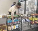  ??  ?? Diego Garcia restocks a food shelf at the Gage Park Latinx Council’s Cultural Center.