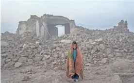  ?? ?? A boy stands Wednesday in front of the remains of his house in Zenda Jan district in Herat province, western Afghanista­n.