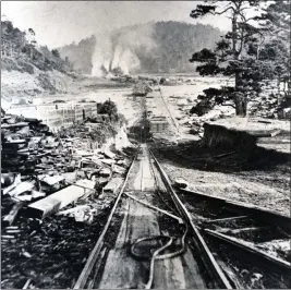  ?? OBJECT ID #1973-182-1218, ALICE EARL WILDER COLLECTION, KELLEY HOUSE MUSEUM ?? A photograph of a stereograp­h showing the Incline on the tramway from the Big River Mill, where the lumber was cut and planed, to the Shipping Point, where it was stored until loaded onto ships that anchored in Mendocino Bay. The mill, seen in the background with smoke around it from the wood-fired boilers for the steam engines, was located on the east end of Big River Beach.