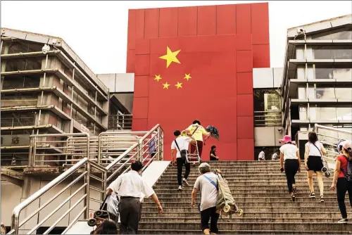  ?? SHEN QILAI / BLOOMBERG ?? Commuters walk toward the boundary-crossing facility at Shatoujiao Port of Entry in Shenzhen. Amid heated debates about the proposed amendment to the country’s Individual Income Tax Law, experts are calling for tax exemption for Hong Kong residents working in the Bay Area to facilitate talent exchanges. tax director at Deloitte China