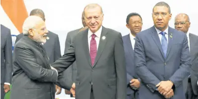  ?? AP ?? Turkey’s President Recep Tayyip Erdogan, centre, shakes hands with Indian Prime Minister Narendra Modi before they pose for a group picture at the emerging national economies (BRICS) summit meeting in Johannesbu­rg, South Africa, July 2018. On the right is Prime Minister of Jamaica, Andrew Holness.
