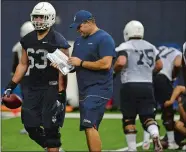  ?? SARAH GORDON/ THE DAY ?? UConn redshirt senior center Ryan Crozier, left, talks with offensive graduate assistant Ben Chapman during the first day of practice Wednesday at the Shenkman Training Center.