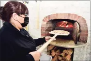  ?? Peter Hvizdak / Hearst Connecticu­t Media ?? Assistant pizza maker Paola Spera puts a pie into Doma’s wood-fired brick oven earlier this month.