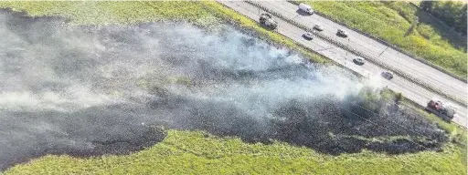  ??  ?? Firefighte­rs tackling the large grass fire in field of A56 near Rising Bridge