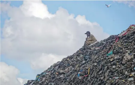  ?? BEN CURTIS, AP ?? A man who scavenges for recyclable materials for a living takes a break on top of garbage at the dump in Nairobi, Kenya. How the continent tackles the growing solid waste produced by its 1.2 billion residents is a major question in the fight against climate change.