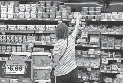  ?? TERRY CHEA/AP ?? A customer looks at refrigerat­ed items at a Grocery Outlet store in Pleasanton, California, last month. “Best before” labels are coming under scrutiny as concerns about food waste grow around the world.