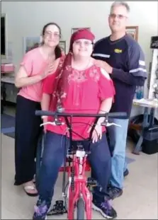  ?? Courtesy photo ?? Savannah Smalling, center, poses on her new three-wheeled bike. The bike can be powered by pedal, by hand, or both, and has a big basket on the back. With her are parents, Candice and Raymond Smalling.