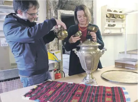  ?? FOTO: KATRIN NEEF ?? Maximilian Eiden und Andrea Maria Schreck bauen einen Samowar zusammen, mit dem Tee zubereitet wird. Ein ehemaliger Gastarbeit­er aus der Türkei hat ihn als Ausstellun­gsstück zur Verfügung gestellt.