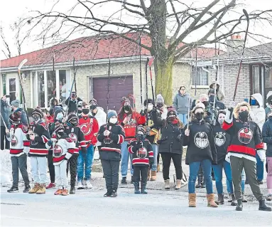  ?? NATHAN DENETTE THE CANADIAN PRESS ?? People lift hockey sticks to pay their respects across the street from where Walter Gretzky's funeral service was being held.