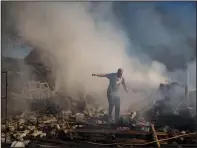  ?? ?? A neighbor walks March 24 on the debris of a burning house that was destroyed after a Russian attack in Kharkiv.