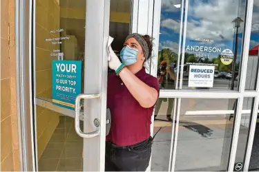  ?? Richard Shiro / Associated Press ?? Kendall Ballew cleans the doors before the Anderson Mall opened in April to limited business in Anderson, S.C. The Associated Press found some governors put economic interest ahead of public health guidance.