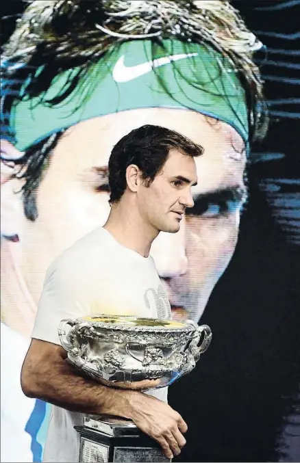  ?? LUKAS COCH / EFE ?? Roger Federer, con su sexta copa en Melbourne, recorriend­o el Rod Laver Arena, ayer