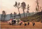  ?? NOAH BERGER/AP ?? Howard Forest Helitack firefighte­rs return to their helicopter after battling the LNU Lightning Complex on Sunday in unincorpor­ated Lake County, Calif.